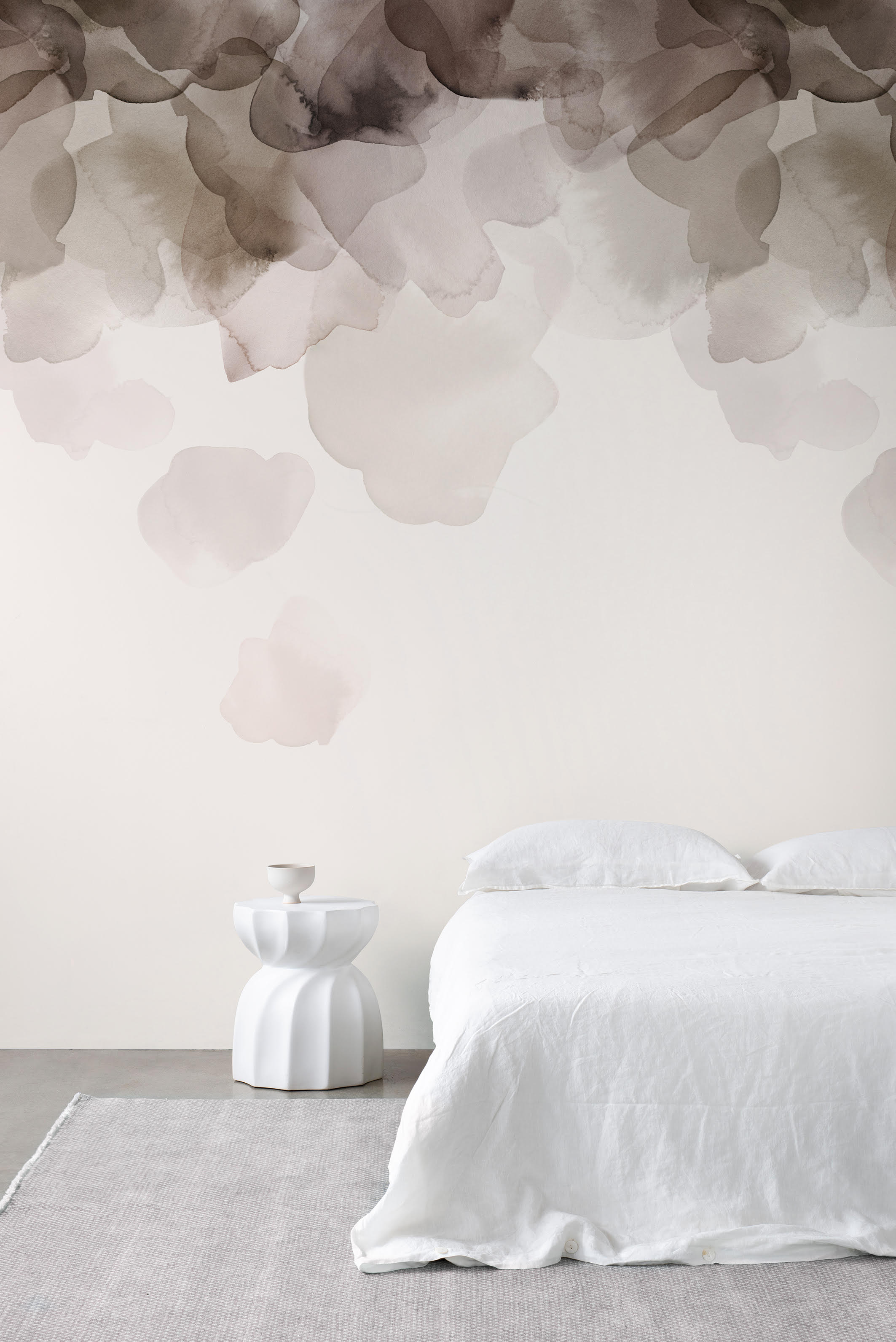 Bloom wallpaper by Emma Hayes in coffee brown, watercolour petals cascading above a white bed