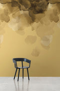 Bloom wallpaper by Emma Hayes in gold, mustard watercolour petals on a vivid yellow wall with a black chair