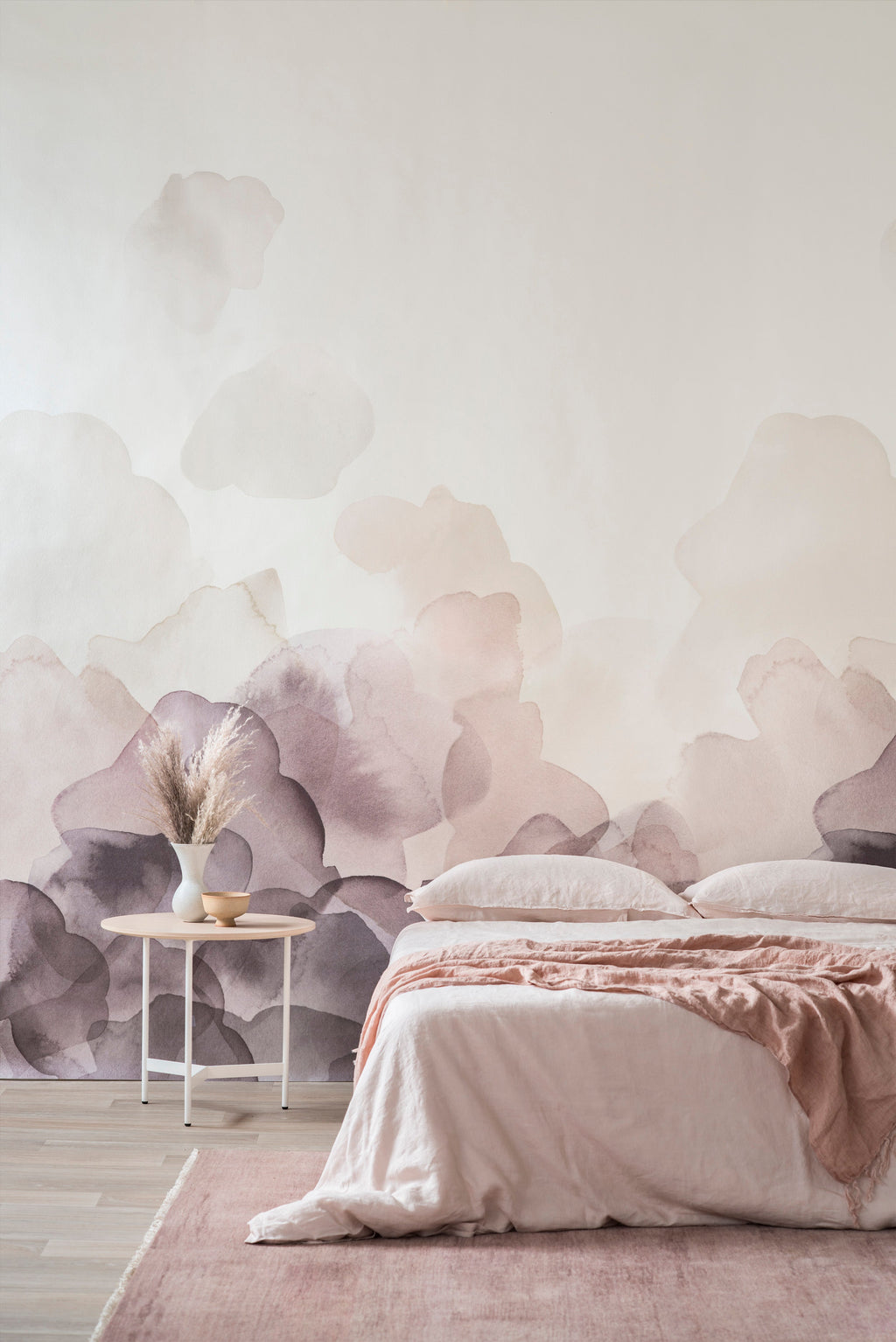 Bloom wallpaper by Emma Hayes in plum, watercolour petals rising up a wall above a blush-toned bed