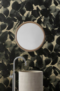 Botanic wallpaper by Emma Hayes in black and gold, inky leaves on a warm gold ground behind a basin