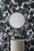 Botanic wallpaper by Emma Hayes in shadow, bold black and grey watercolour leaves around a round mirror