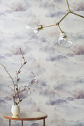 Cloud wallpaper by Emma Hayes in Mauve, soft mauve and grey watercolour clouds behind a brass light and a vase of branches
