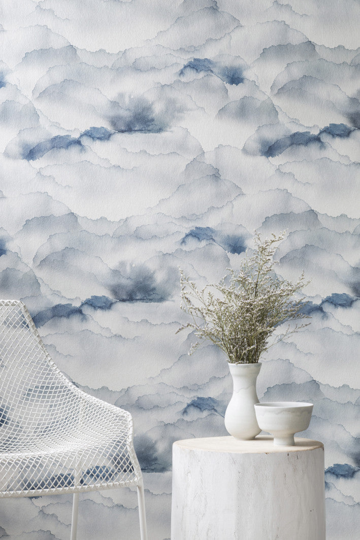 Cloud wallpaper by Emma Hayes in Sky, blue watercolour clouds styled with a white wire chair and marble side table