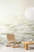 Desertscape wallpaper by Emma Hayes in green, sage and cream brushstroke waves styled in a living room with woven chair and paper lantern
