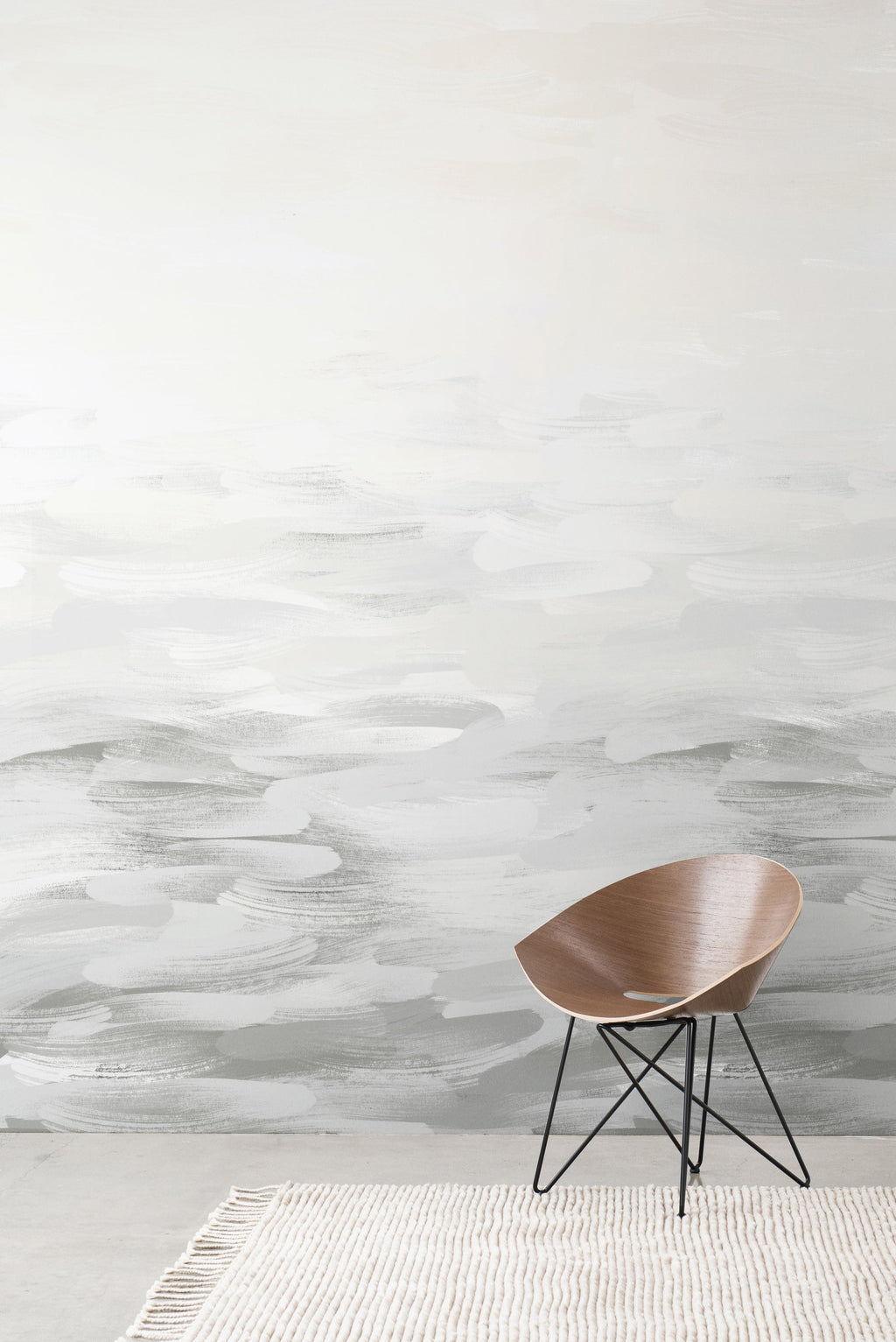 Desertscape wallpaper by Emma Hayes in soft grey and ivory painterly waves behind a wooden bentwood chair on a textured rug