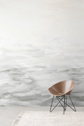 Desertscape wallpaper by Emma Hayes in soft grey and ivory painterly waves behind a wooden bentwood chair on a textured rug