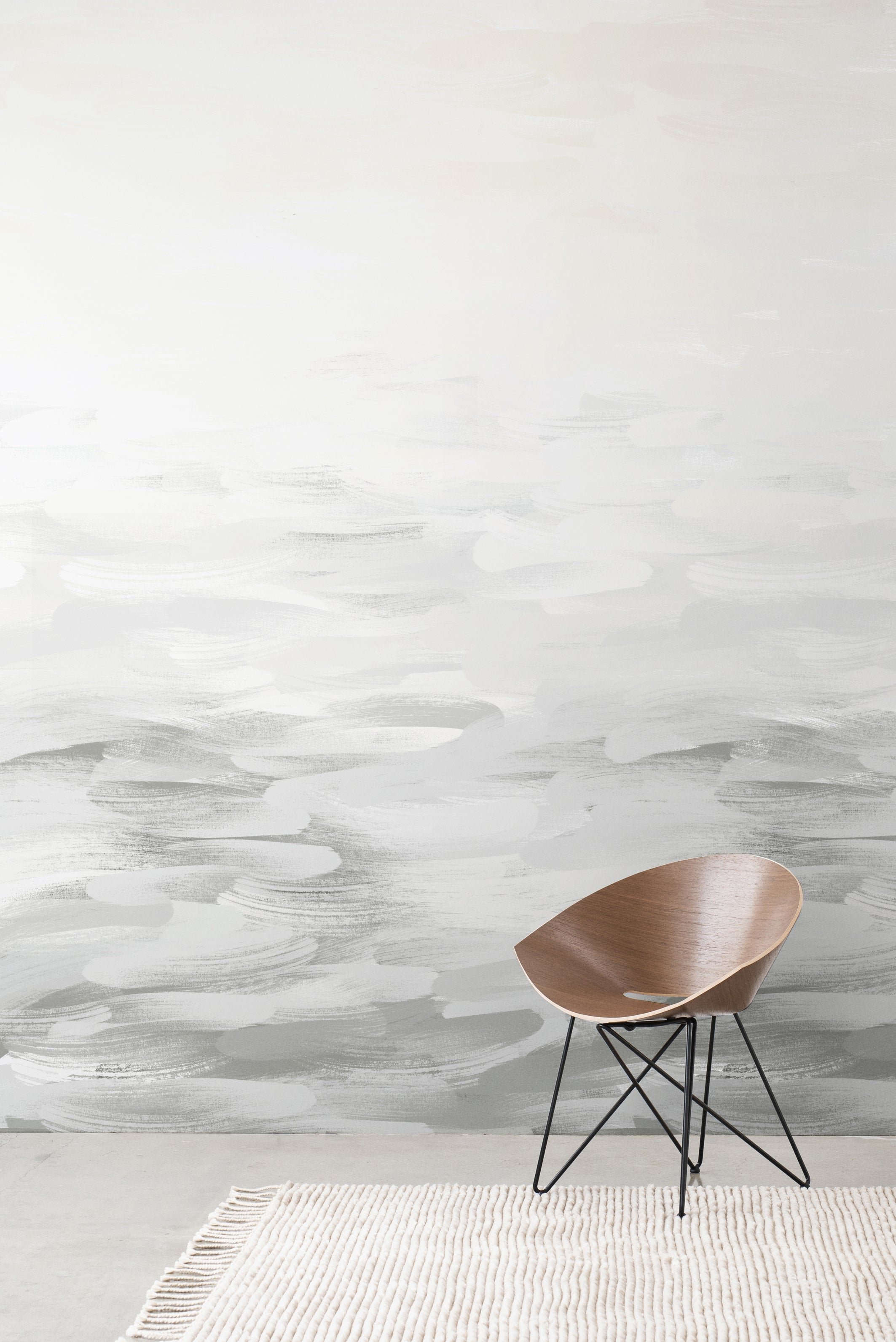 Desertscape wallpaper by Emma Hayes in soft grey and ivory painterly waves behind a wooden bentwood chair on a textured rug