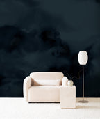 Dispersion wall mural by Emma Hayes in Midnight, deep navy ink clouds behind a cream armchair and floor lamp