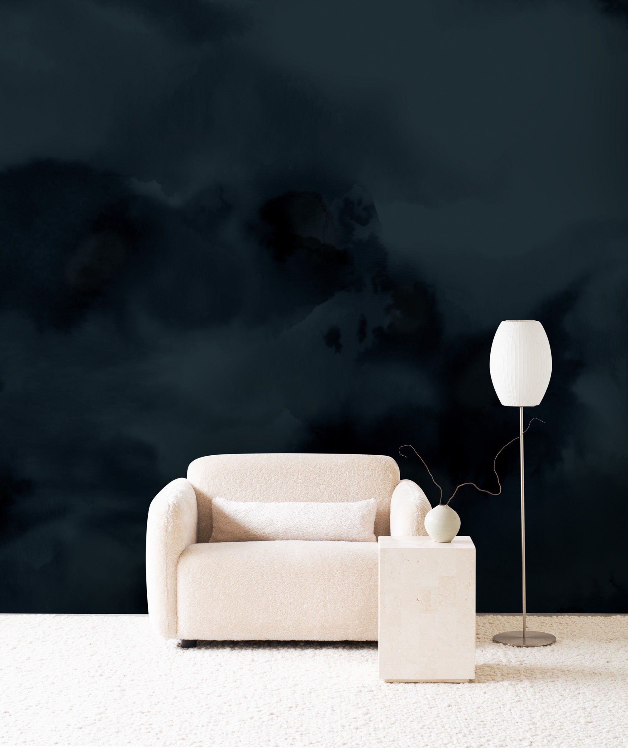 Dispersion wall mural by Emma Hayes in Midnight, deep navy ink clouds behind a cream armchair and floor lamp