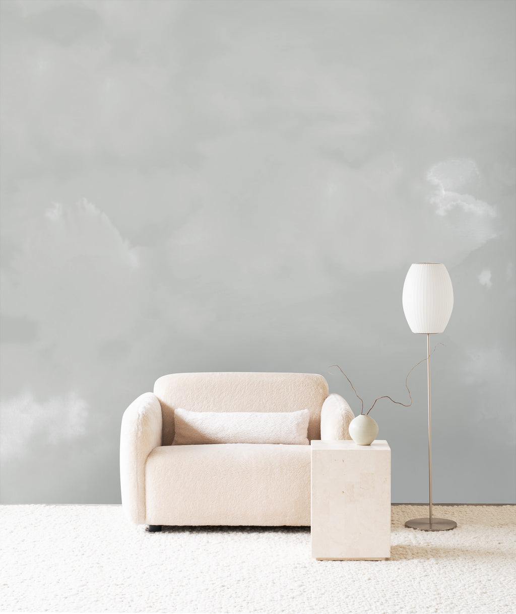 Dispersion wall mural by Emma Hayes in Mist, soft grey watercolour cloud forms behind a cream sofa