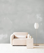 Dispersion wall mural by Emma Hayes in Mist, soft grey watercolour cloud forms behind a cream sofa