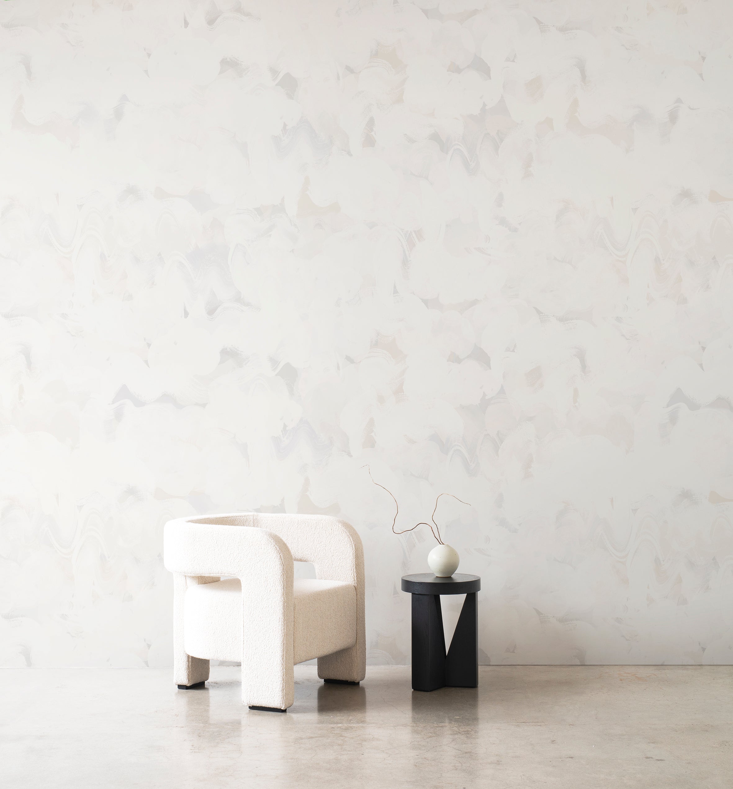 Dreamer wallpaper by Emma Hayes in Buff, soft cream painterly brushstrokes behind a white boucle armchair