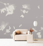 Drift wall mural by Emma Hayes in Dusk, cream foliage silhouettes on a soft mauve-grey ground behind a boucle sofa