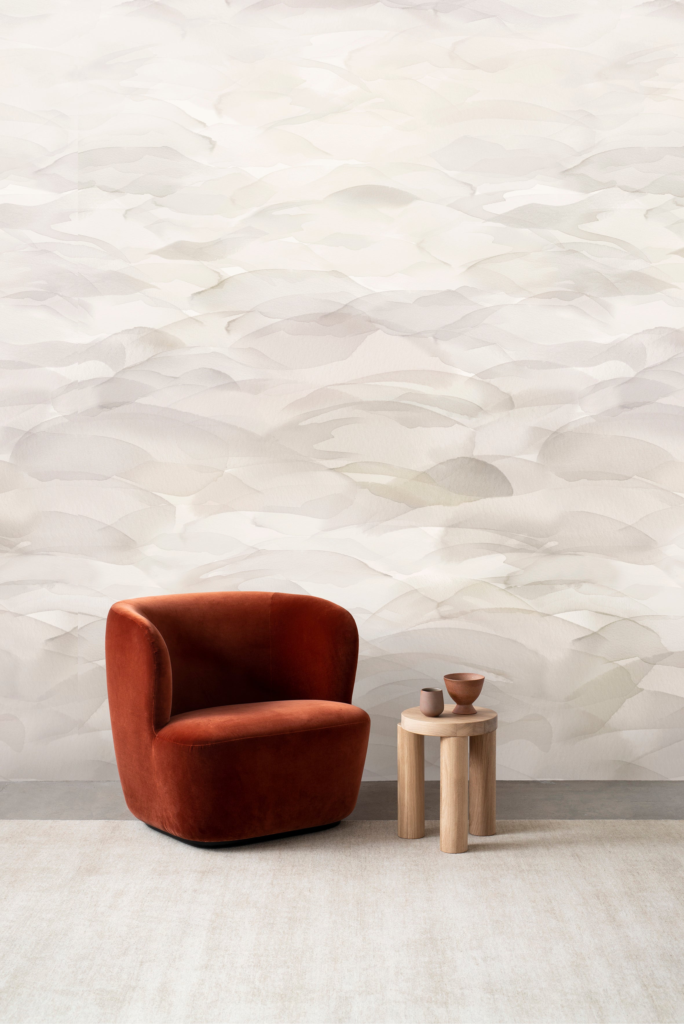 Dune wall mural by Emma Hayes in Buff, soft cream and pale beige watercolour dunes behind a rust velvet armchair
