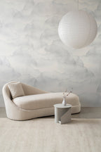 Nebula wallpaper by Emma Hayes in soft grey mist, a watercolour cloud sky design, styled behind a cream boucle chaise in a calm living room