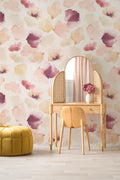 Petals Pressed wallpaper by Emma Hayes in blush pink and plum, soft watercolour petals on cream, styled behind a rattan dressing table