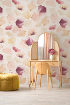 Petals Pressed wallpaper by Emma Hayes in blush pink and plum, soft watercolour petals on cream, styled behind a rattan dressing table