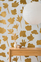 Petals Pressed wallpaper by Emma Hayes in mustard gold, bold painted petal silhouettes on pale grey, styled behind a timber console table