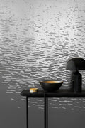 Reflection wallpaper by Emma Hayes in metallic silver on grey, rippling water-reflection pattern, styled behind a black