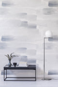 River wall mural by Emma Hayes, pale watercolour washes in blue-grey across a feature wall behind a dark bench with eucalyptus and books