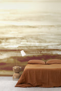 Sediment wall mural by Emma Hayes in Earth, warm sand and rust watercolour layers styled behind a bed dressed in terracotta linen with a timber lamp