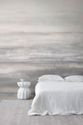 Sediment wall mural by Emma Hayes in Greystone, soft tonal grey watercolour bands styled in a serene bedroom with white linen and pale rug