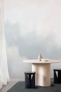 Solar wall mural by Emma Hayes in Fossil, muted grey-blue smoky haze behind a wavy stone dining table and dark stools