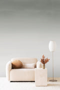Stratum ombre wall mural by Emma Hayes in muted sage green washing to white, styled in a living room with a cream sofa