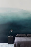 Wash wall mural by Emma Hayes in teal reef watercolour tones, styled in a bedroom with grey bedding and bedside lamp