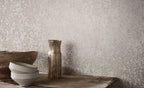 Nyiri wallpaper by Romo, a soft mottled limewash texture in pale grey, styled with stoneware bowls on a timber bench