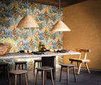 Avicennia wallpaper by Casamance in emerald and mustard, a dense protea and foliage print styled in a dining room with woven rattan pendants and a stone table