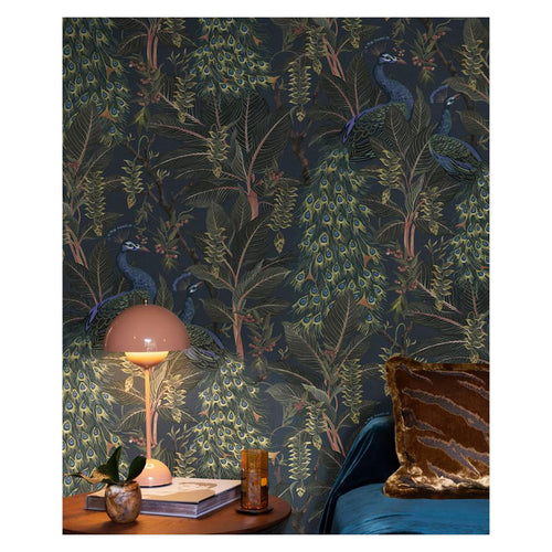 Royal Peacock wallpaper by Catherine Martin in sapphire blue styled on a bedroom wall with a pink table lamp and velvet