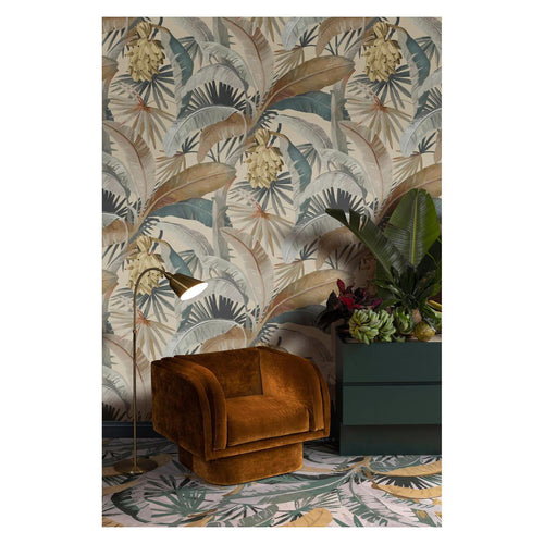 La Palma wallpaper by Catherine Martin styled in a living room, soft sage and tan palm leaf print behind a tan velvet armchair