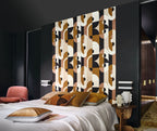 Vassily wallpaper by Casamance in bronze and ochre, a bold geometric design styled on a panel behind a bed in a dark room