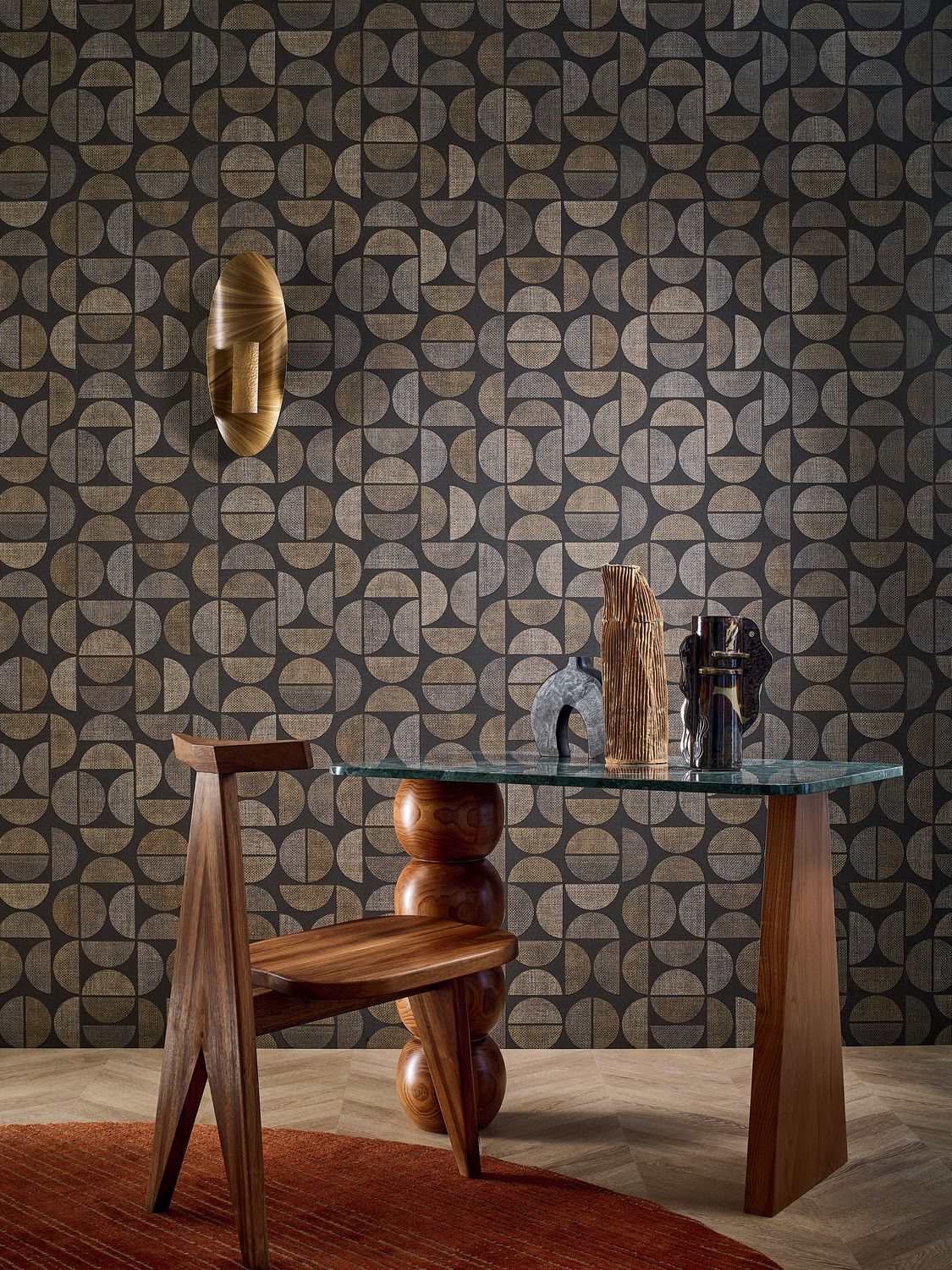 Dualis wallpaper by Casamance in brown and charcoal, a woven semicircle geometric styled behind a sculptural walnut chair