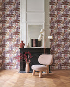 Marakanda wallpaper by Casamance in rosewood and cream, a blossoming tree design styled beside a fireplace with a pink armchair