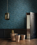 Sohar wallpaper by Casamance in navy and gold, a rippling wave texture styled beside a panelled door with ceramic vessels