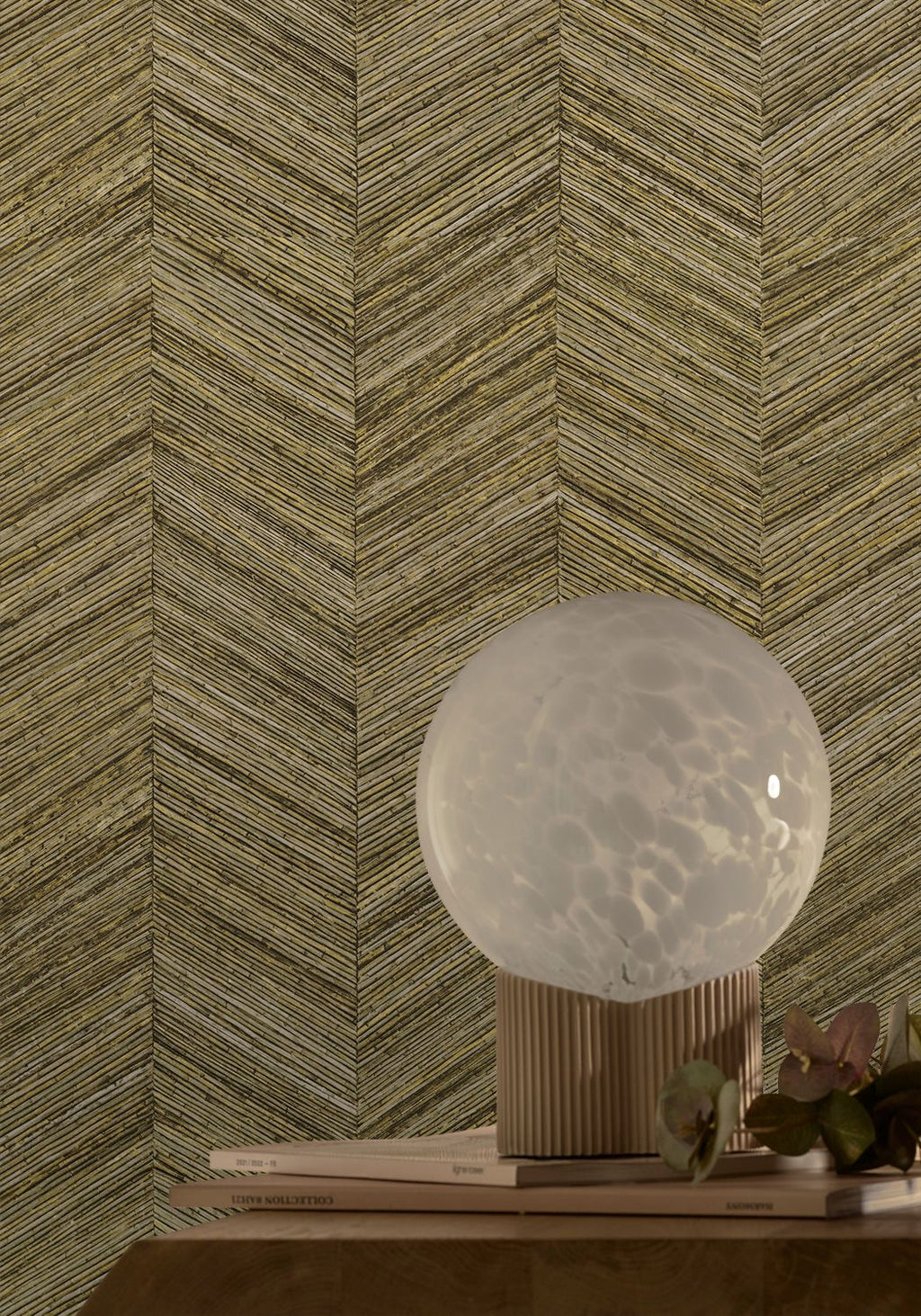 Ocotea wallpaper by Casamance in khaki, a chevron grasscloth weave styled behind a globe lamp on a timber plinth