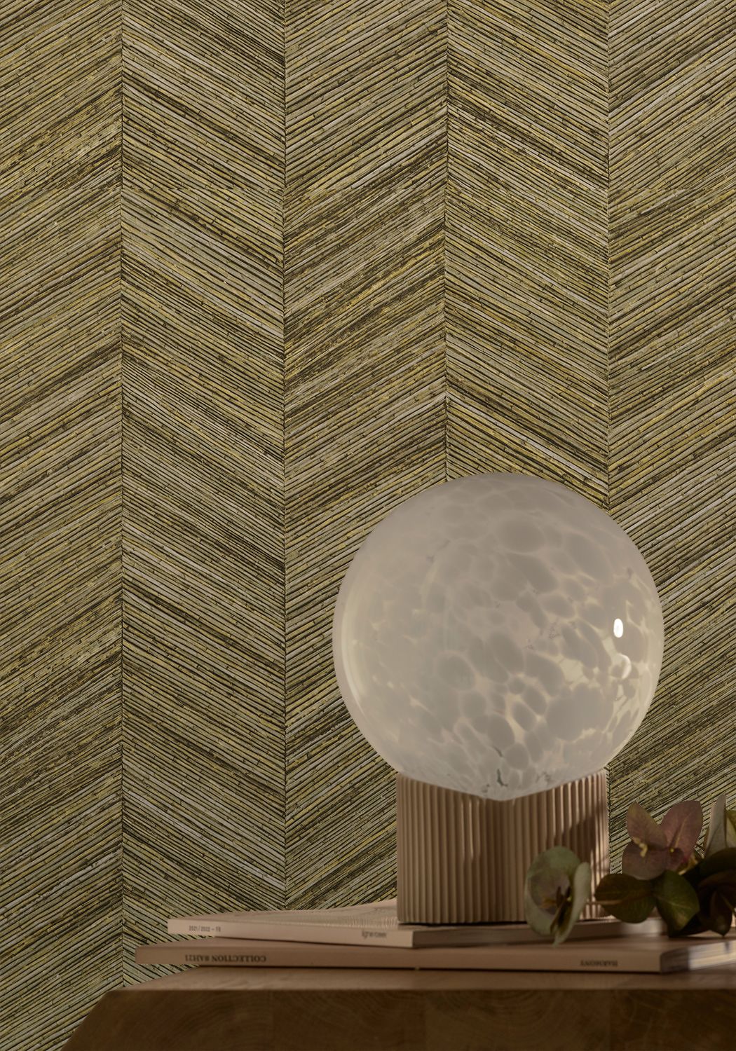 Ocotea wallpaper by Casamance in khaki, a chevron grasscloth weave styled behind a globe lamp on a timber plinth