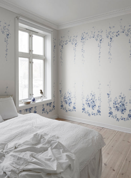 Marieberg blue floral wall mural by Sandberg in a white bedroom with linen bedding and a bird on the windowsill