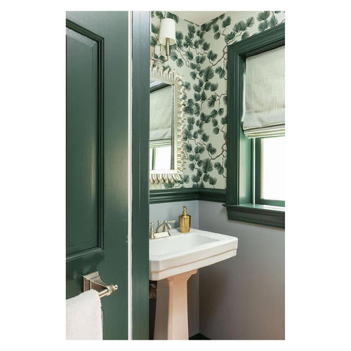 Pine wallpaper by Sandberg in green on a powder room wall with a green-painted door, mirror and pedestal basin