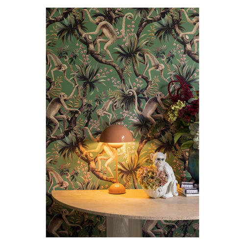 Monkey Business wallpaper by Catherine Martin in ming green styled on a wall with a terracotta lamp and white monkey ornament