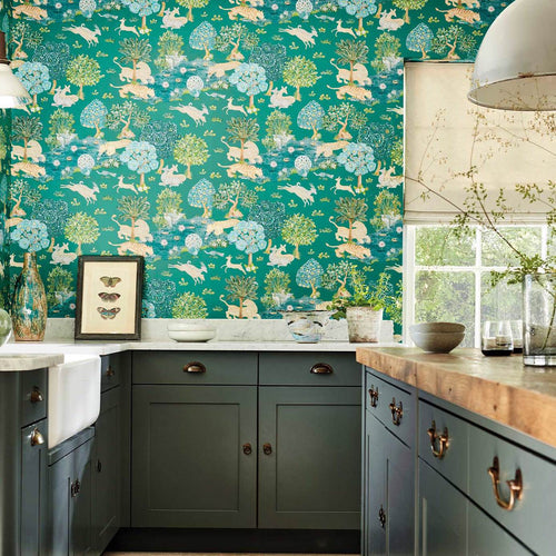Pamir Garden Teal wallpaper by Sanderson in a kitchen above sage-green cabinetry, animal-and-tree garden motif on a teal